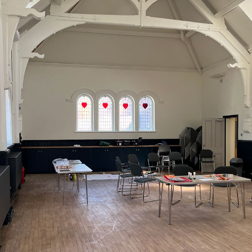 Century Hall - a hall  with chairs and tables. There are windows with heart-shaped stained glass.