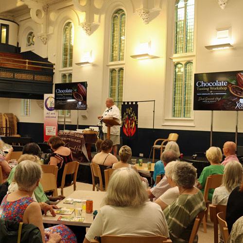 Trinity-Hall-at-The-Link-Centre-Ashbourne---seating-at-tables-2 Trinity Hall at The Link Centre with people sitting at tables looking at someone on stage talking about chocolate