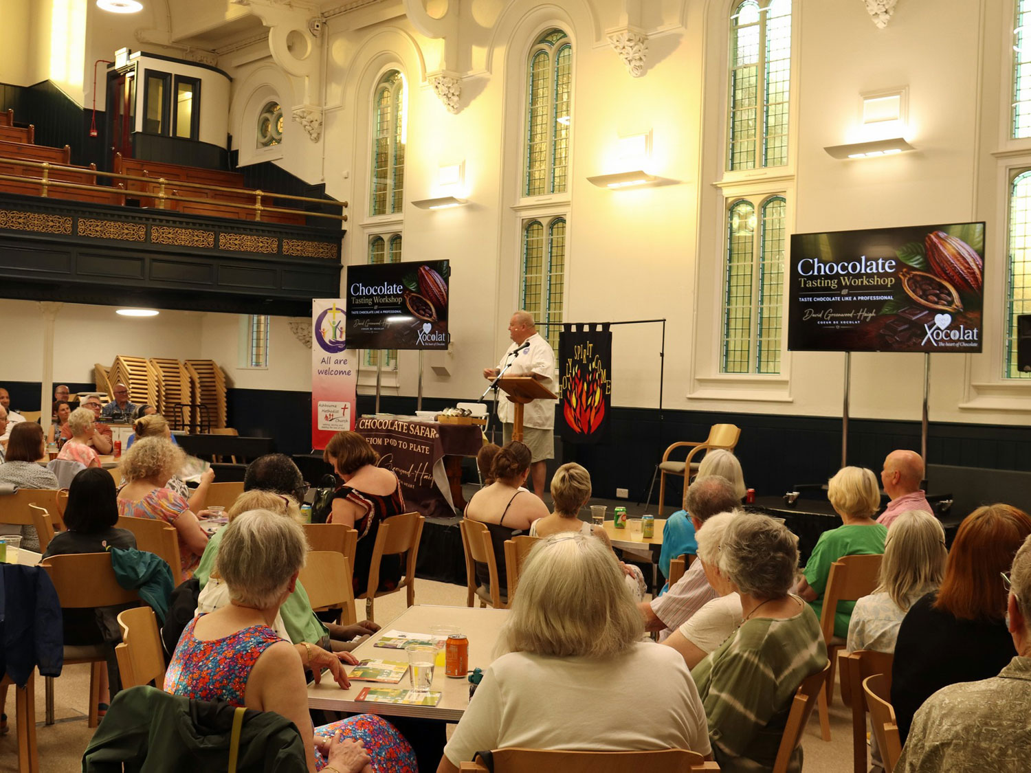 Trinity Hall at The Link Centre with people sitting at tables looking at someone on stage talking about chocolate