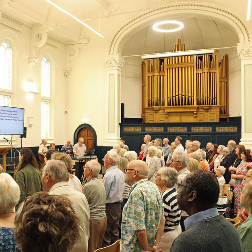 A photo of a church service in Trinity Hall at The Link Centre. There is a large congregation.